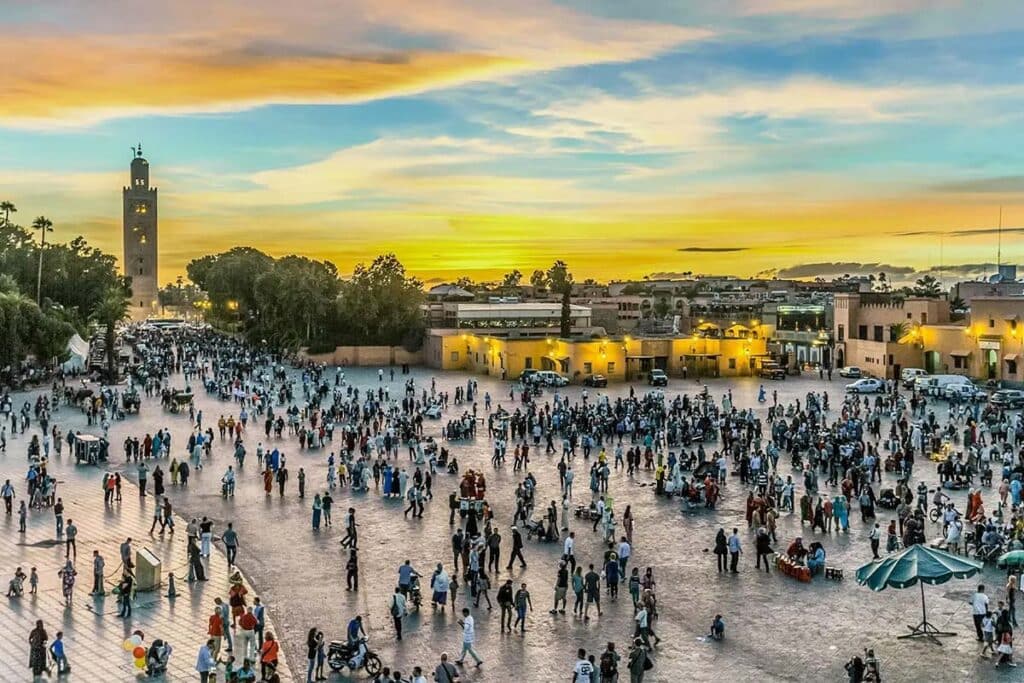 Rooftop sunset view of Jemaa el-Fnaa square with Koutoubia minaret glowing in Marrakech