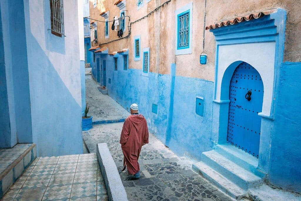 Elderly man walking through a blue-painted alley in Chefchaouen, Morocco things to do