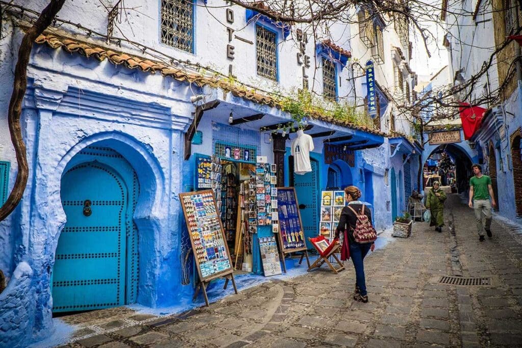 Blue‑painted alley with souvenir stalls in Chefchaouen medina, Rif Mountains, Northern Morocco