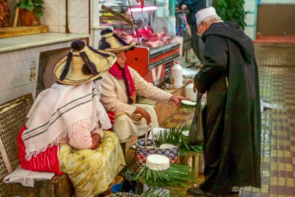 Rif Berber women in traditional straw hats selling fresh jben goat cheese at Tangier market