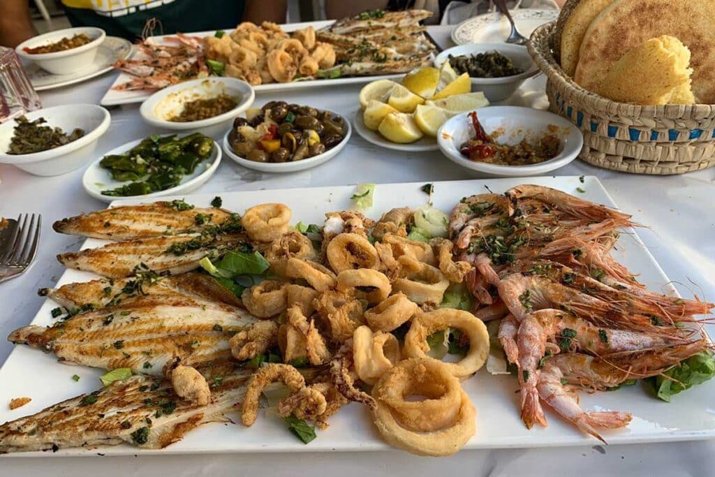 Platter of grilled sole, fried calamari and prawns with Moroccan salads and khobz bread in Tangier seafood restaurant