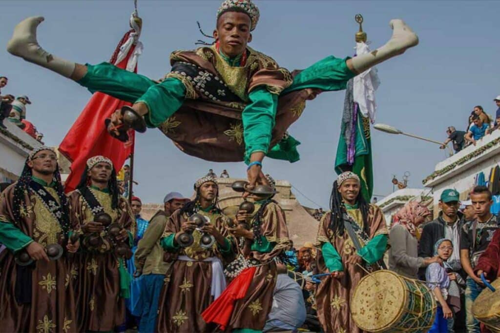 Gnawa dancer midair above musicians during a street performance in Essaouira